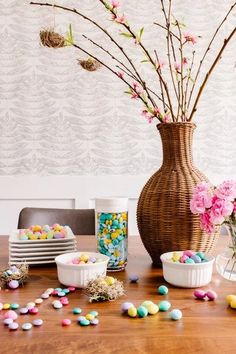 the table is covered with candy and flowers in vases next to plates, bowls and cups