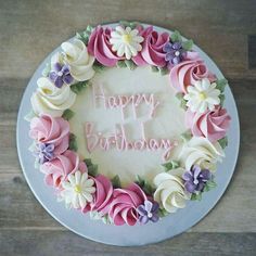 a birthday cake with pink, white and purple frosting flowers on it that says happy birthday