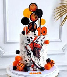 a birthday cake decorated with basketballs and balls on a pedestal in front of a white wall