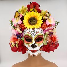 a woman's face is decorated with flowers and butterflies for day of the dead