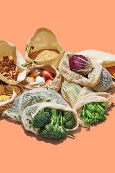 several bags filled with different types of vegetables and grains on top of each other in front of an orange background