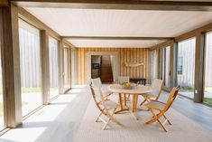 a table and chairs in a room with sliding glass doors on the outside side of the house