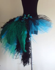 a black mannequin with blue and green feathers