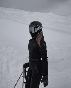 a woman standing on top of a snow covered slope wearing skis and holding ski poles