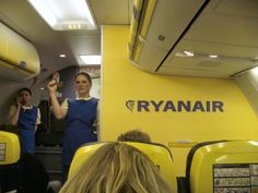 a woman in blue overalls standing on an airplane with her hand up to the air