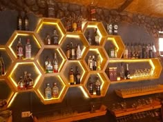 the shelves are filled with liquor bottles and glasses on them, along with lights that look like hexagonal honeycombs