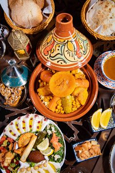 a table topped with lots of plates and bowls filled with different types of food on top of it