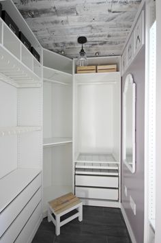 an empty walk in closet with white shelves and drawers