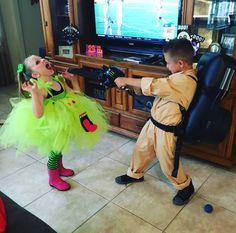 two children dressed up in costumes playing video games on the television set while one child watches