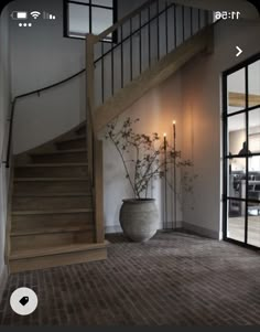 a vase with flowers sitting on the floor next to a stair case in a house