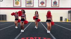 three cheerleaders in red and black outfits are dancing on the basketball court with their pom poms