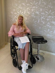 a woman sitting in a wheel chair next to a wall