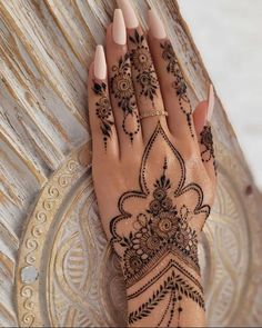 a woman's hand with henna tattoos on it, resting on a plate