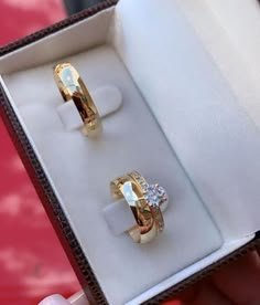 two yellow gold rings in a box with diamonds on the top and bottom, sitting next to each other