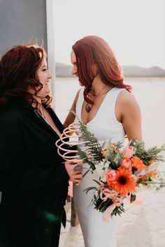 two women standing next to each other holding flowers