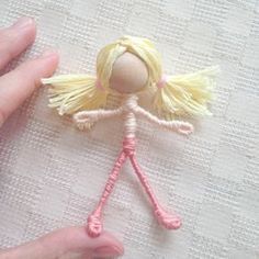 a hand is holding a small doll made out of yarn