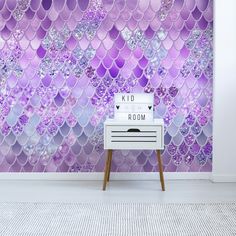 a room with purple mermaid scales on the wall and a white table in front of it