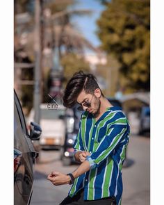 a man standing next to a car looking at his cell phone