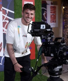 a man standing next to a camera on top of a tripod