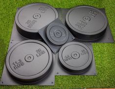 four black round plates sitting on top of green carpeted floor next to each other