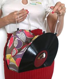 a woman in white shirt and red skirt holding a black purse with colorful designs on it