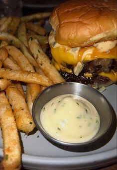 a cheeseburger and fries on a plate with a small bowl of ranch dressing