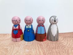 three little pigs are standing next to each other on a wooden table with white wall in the background