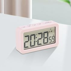 a pink alarm clock sitting on top of a table