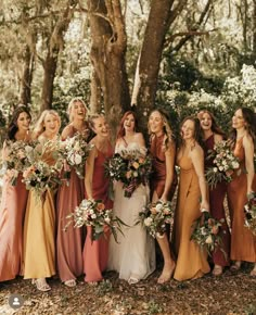 a group of women standing next to each other in front of a tree holding bouquets