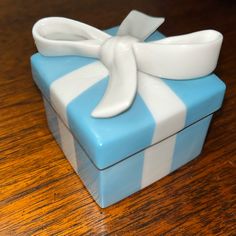 a small blue and white box with a bow on it's lid sitting on a wooden table