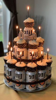 a birthday cake made out of beer cans with lit candles in the top tiers