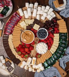 a platter filled with fruit, marshmallows, and other snacks on skewers