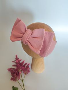 a wooden head with a pink bow on it