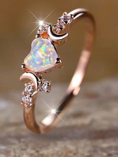 an opal and diamond ring on top of a rock