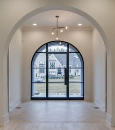 an arched window in the middle of a room with wood flooring and white walls