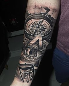 a man's arm with a compass and an eye tattoo on the left forearm