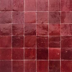 a red tiled wall with small white dots on the top and bottom tiles in different colors