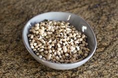 a bowl filled with black eyed peas sitting on top of a granite counter next to a knife