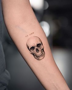 a person with a skull tattoo on their arm and the word'the dead'written in black ink