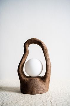 a wooden sculpture with an egg in it's shell on a white tablecloth