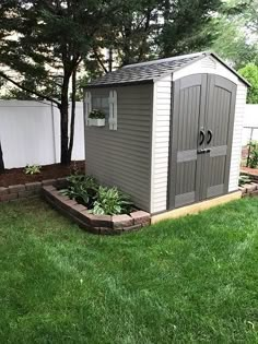 a small shed sitting on top of a lush green field next to a white fence