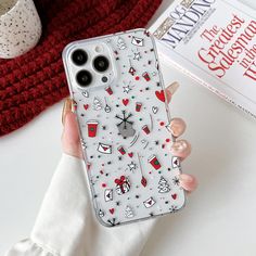 a woman holding up her phone case with christmas decorations on it and a book in the background