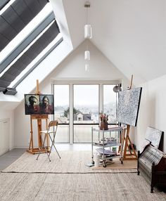 an artist's studio with easels and paintings on the floor in front of large windows