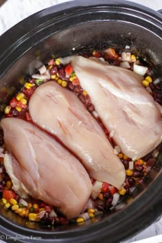 two pieces of chicken in a crock pot with corn