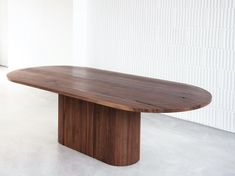 a large wooden table sitting on top of a white floor next to a wall and window