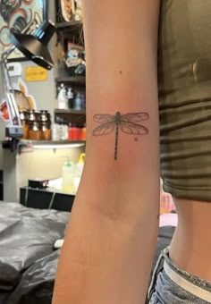 a woman's arm with a small dragonfly tattoo on the left side of her arm