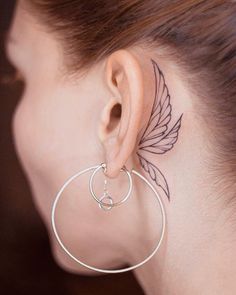 a close up of a person with a tattoo on their left side of the ear