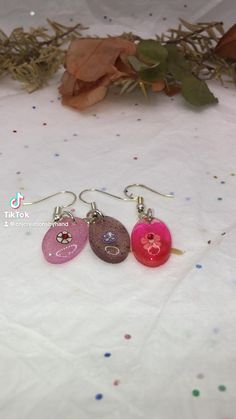 Handmade oval resin floral dangle earrings. There are four colors to chose from. Hypoallergenic for sensitive skin. Minimalist earrings and light weight. Cute resin dangle earring. Each earring has a clay flower jewel with a jewel in the middle of each flower. The colors are made with orange and red alcohol ink, purple dye with purple glitter, pink dye with pink glitter. #earrings #dangle #dangling #dangledropearrings #jewelry #resin #resinearrings #lightweightearrings #hypoallergenic #flowers #floral #unique #uniquejewellery #etsy #etsyseller #etsyshopowner #glitter #pink #purple #red #oval Resin Crochet, Jewelry Painting, Painting Wood, Jewelry Resin, Glitter Earrings