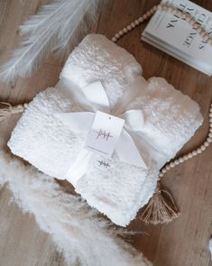 two towels wrapped in white and tied with a ribbon on top of a wooden table