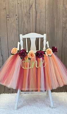 an orange and pink tulle skirt sitting on top of a white chair with flowers